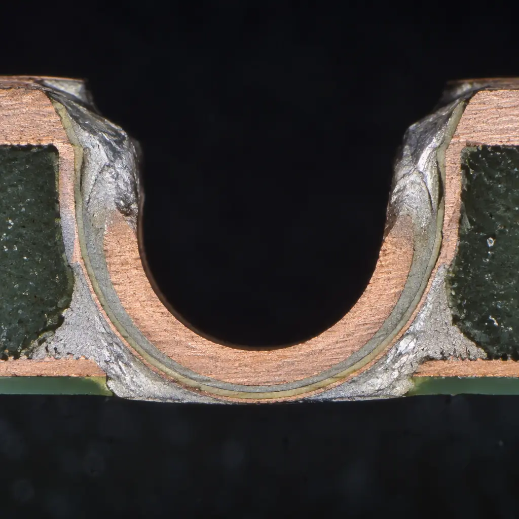 Photomicrograph cross-section through a reflowed castellated joint showing solder fillet on both faces of the half-cylinder
