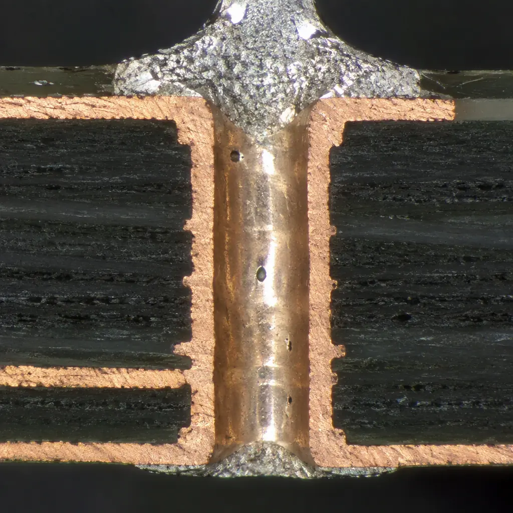 Photorealistic macro photograph of a metallographic microsection of a plated through-hole showing copper barrel wall and solder fillet
