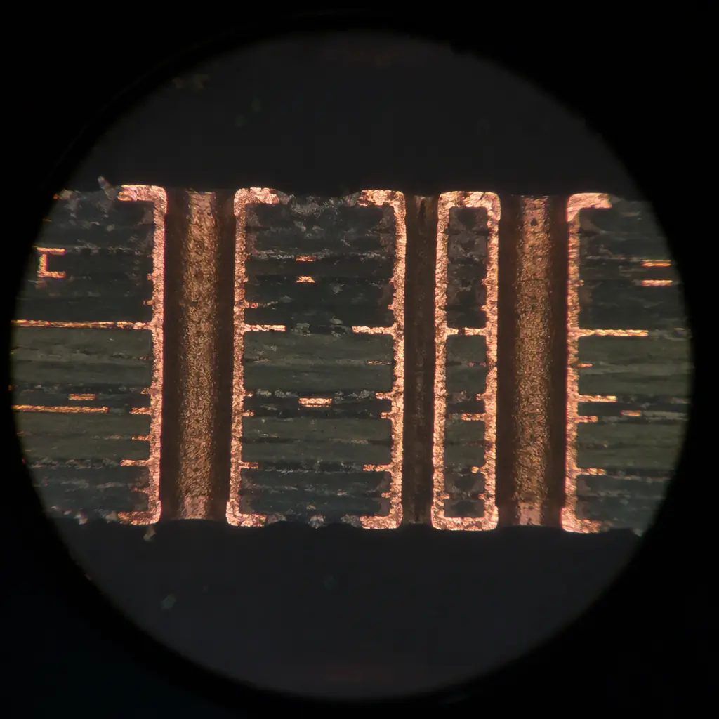 Macro photo of a polished microsection cross-section of a PCB showing plated through vias under a microscope